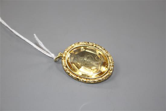 A late Victorian gilt metal mounted oval citrine pendant, engraved with a crested initial,